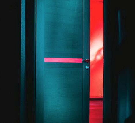 Porte entrouverte bleu-vert laissant filtrer une lumière rouge, salle Hannibal chez Délivrés à Pau