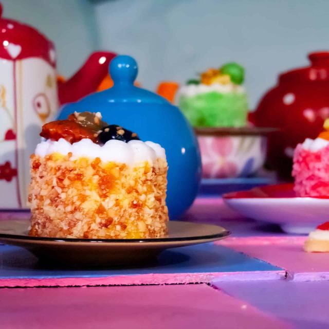Gâteaux colorés, théières rouges et bleues sur une table rose, salle Au pays des merveilles chez Locked Time à Marseille