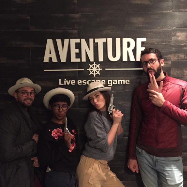 Quatre joueurs en costumes Western posent devant le logo Aventure Live! Escape Game à Nice