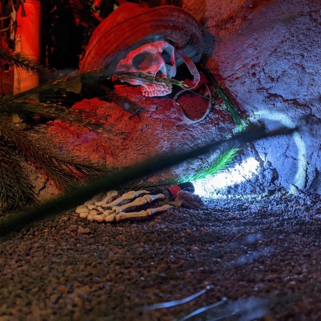 Squelette à demi caché dans une grotte éclairée de rouge et de vert, salle La jungle chez GG Escape Game à Paris