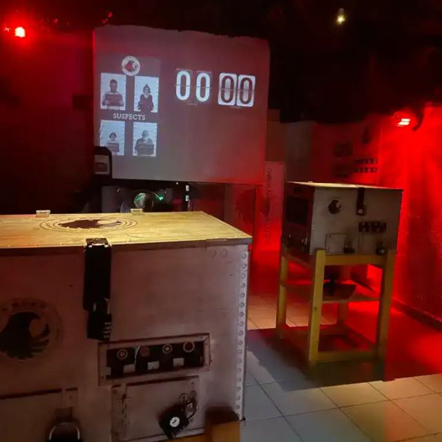 Salle éclairée de rouge avec poste de commande en bois et écran au fond, salle SCEP Unité Spéciale, Puzzle animations