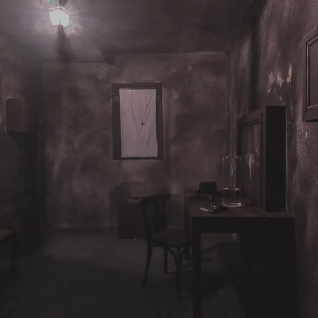 Pièce sombre aux murs usés, bureau avec chaise et fenêtre, chez Game Over Geneva
