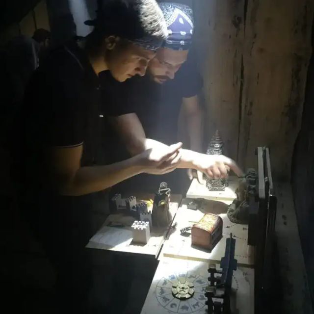 Deux joueurs penchés sur une manipulation à la lampe, salle Le Tour du monde chez Puzzle animations