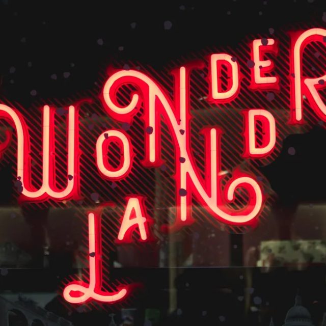 Enseigne néon rouge Wonderland aux lettres entrelacées sur fond sombre, Time Out Real Escape Game à Marseille