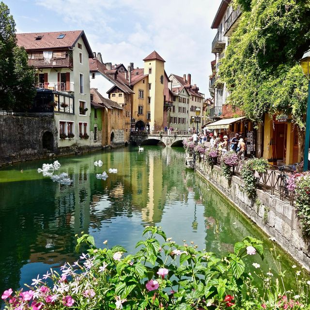 Canal fleuri bordé de balcons et de maisons colorées, jeu urbain Hunting Town à Annecy