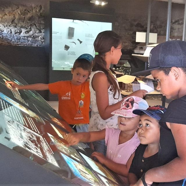 Enfants et adolescents autour d'une table d'exposition interactive, circuit La Grande Vadrouille au Fort Teremba à Moindou