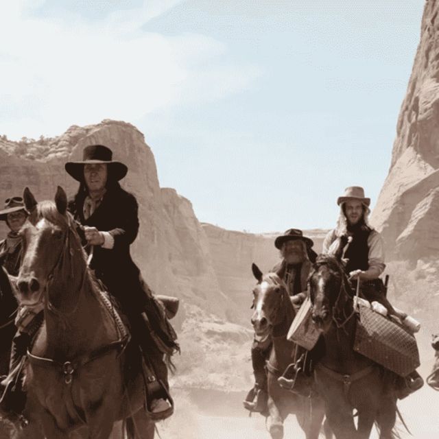 Cavaliers en costume western chevauchent dans un canyon rocheux poussiéreux