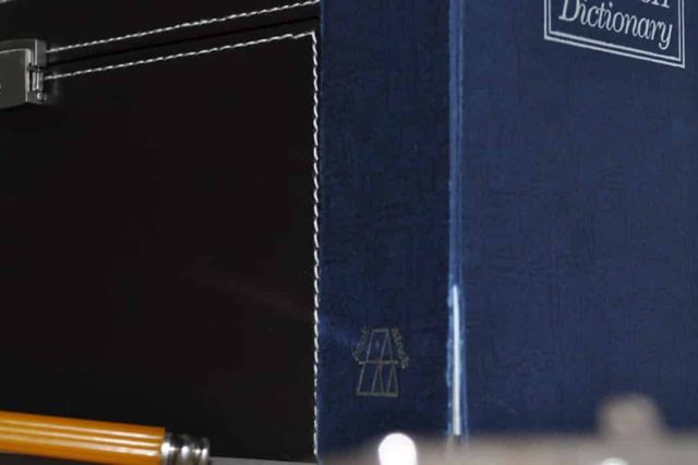 Livre à couverture bleue, dictionnaire et rasoir à manche orange sur une étagère, salle L'Atelier chez IRL Games