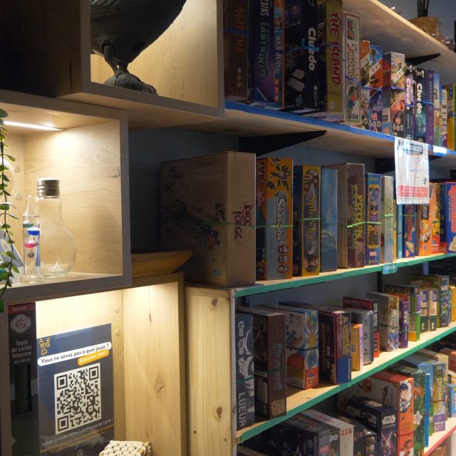 Étagères illuminées remplies de jeux de société colorés chez Break Out à Sévrier