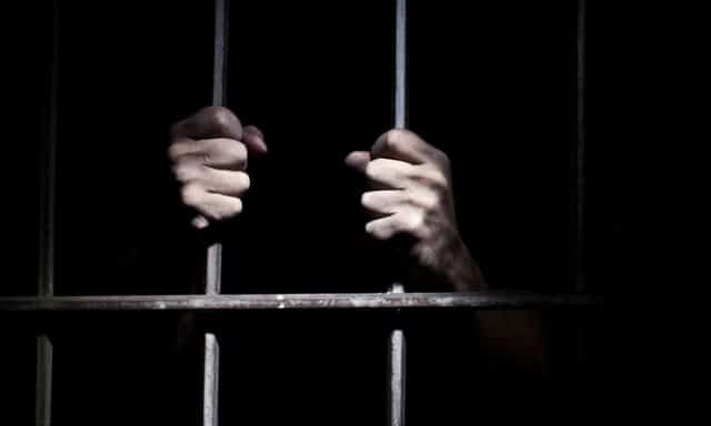 Mains agrippant les barreaux d'une cellule, ambiance carcérale sombre pour Épisode 2 : In prison