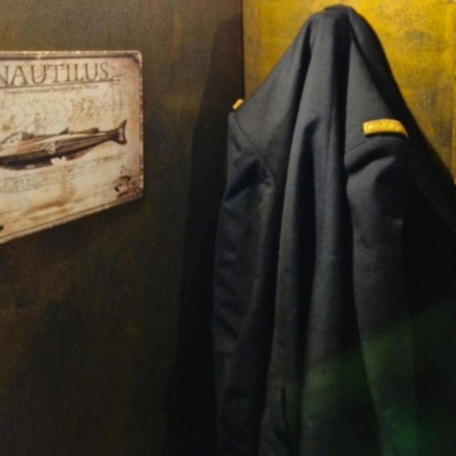 Plaque Nautilus et veste d'officier accrochée à un mur doré, salle Sur les traces du magicien chez Magicbus à Potelle