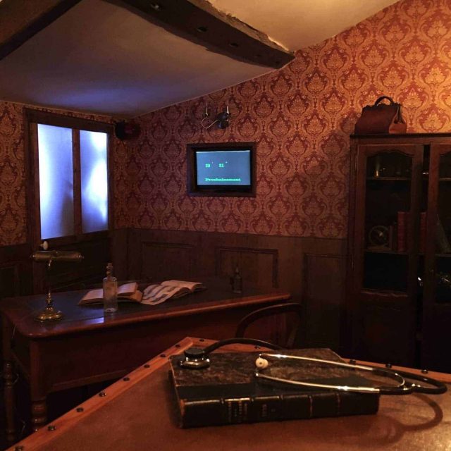 Décor rétro années 1950, papier peint damassé bordeaux, bureau en bois massif, objets médicaux anciens, ambiance d'asile psychiatrique