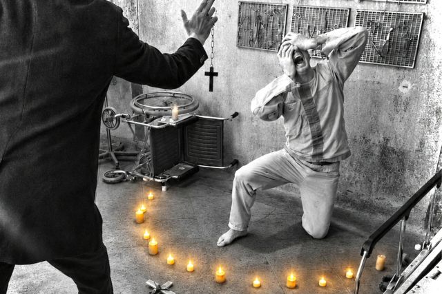 Scène d'exorcisme en noir et blanc, un homme à genoux dans un cercle de bougies, Murder Asylum