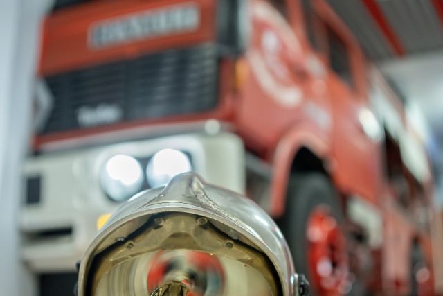 Casque de pompier posé devant un camion rouge dans une caserne, salle Alerte chez les pompiers, Escape League à Poitiers