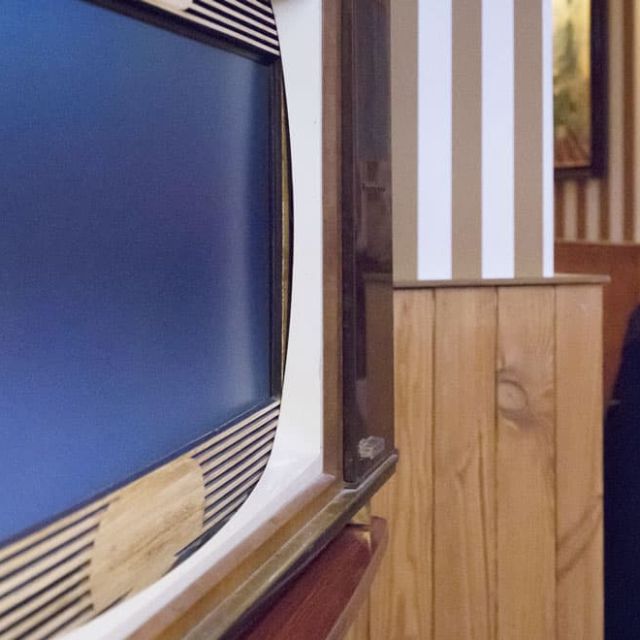 Téléviseur ancien, boiseries et meuble blanc dans une chambre rayée, salle Sunhill Hotel chez Escape Time à Saint-Herblain