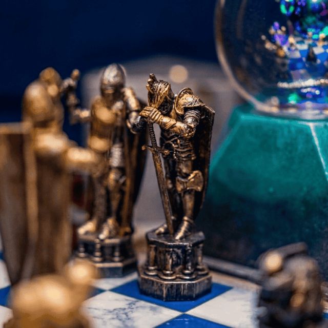 Pièces d'échecs dorées sur un damier bleu et blanc près d'une boule de cristal, salle Le sorcier maudit, BlackOut Room