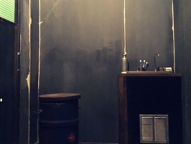 Cellule sombre avec murs gris, bureau en bois et objets dispersés chez Escape Max à Argenteuil