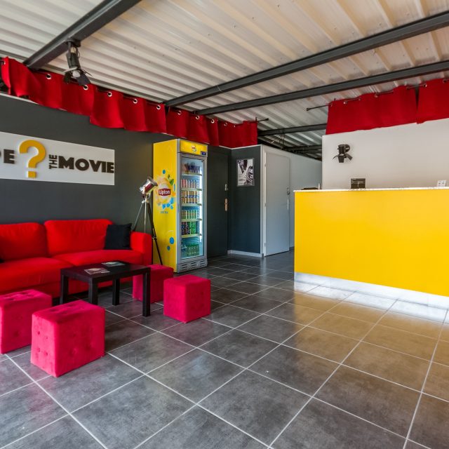 Accueil coloré avec canapé rouge, mobilier design et logo de Escape: The Movie à Marseille