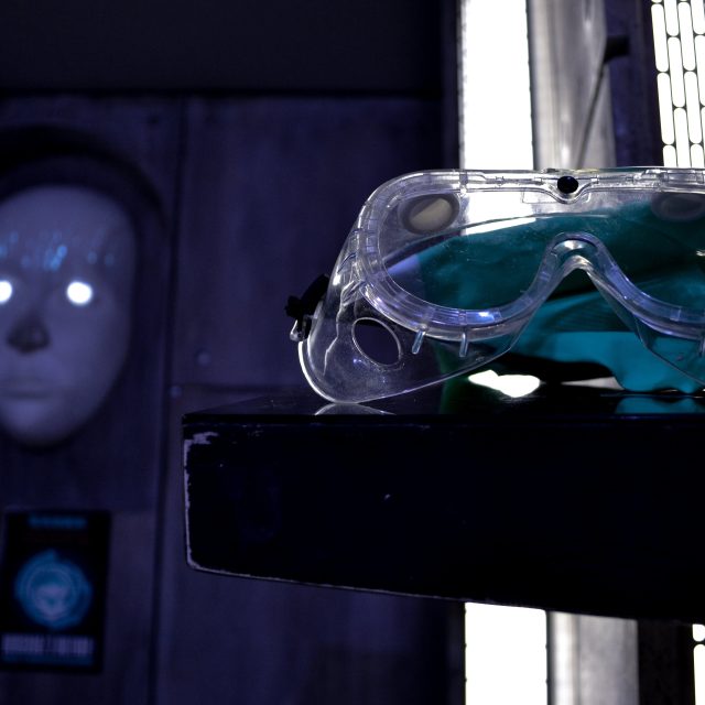 Lunettes de protection et masque luminescent bleu dans décor futuriste Prizoners Paris