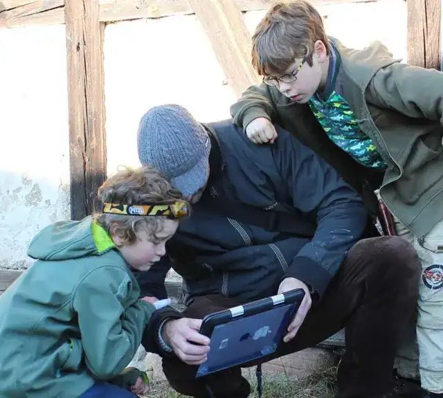 Trois enfants penchés sur une tablette dans la rue, jeu Portail Magique à Lausanne