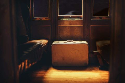 Valise vintage éclairée dans un compartiment de train aux portes en bois sombre
