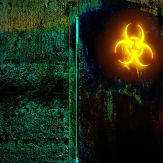 Porte de laboratoire marquée d'un sigle biohazard jaune sur un mur vert, salle Le virus CR-15 chez Black Out à Altkirch