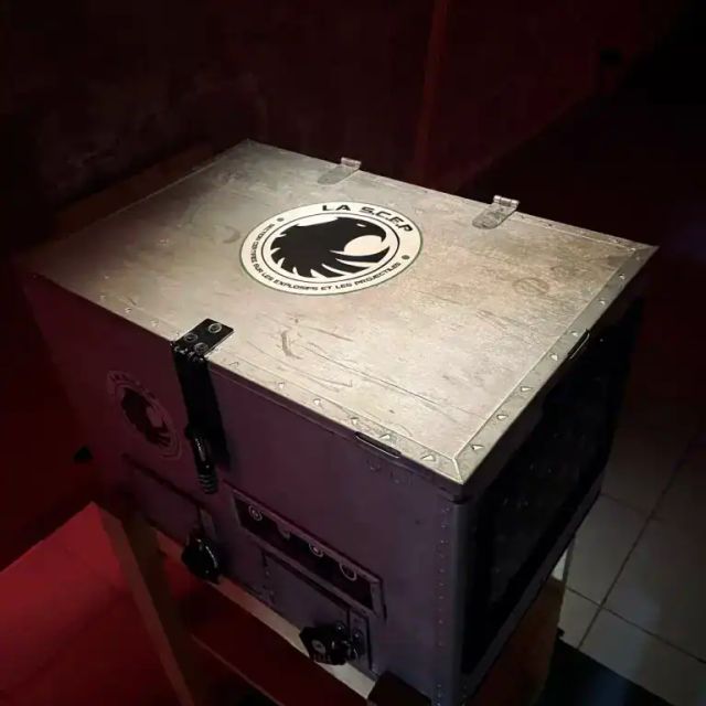 Boîtier de bois blanc à logo de loup posé sur une table dans le noir, salle SCEP Unité Spéciale à Grenoble