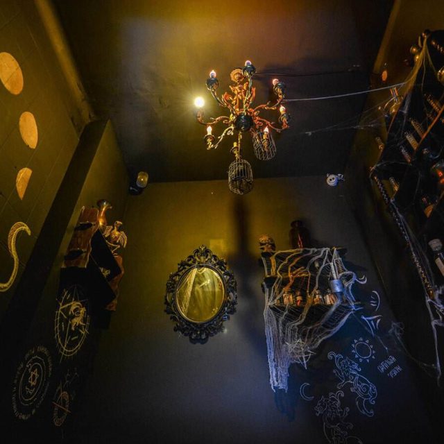 Décor steampunk doré avec chandeliers, cadres ornés et symboles mystérieux dans Un monstre dans le placard