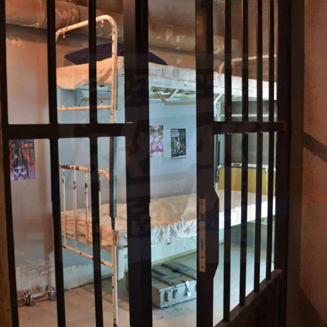 Vue d'une cellule de prison avec barreaux métalliques et mobilier spartiate chez Team Break Lille