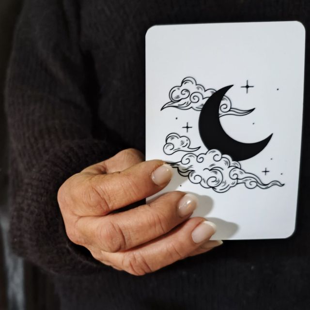 Main tenant une carte blanche ornée d'un croissant de lune et de nuages, salle Loup Garou chez Goodlock à Bordeaux
