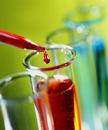 Pipette déposant une goutte rouge dans un tube à essai, salle Le laboratoire chez 01 Mystery