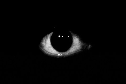 Œil grand ouvert dans l'obscurité totale, visuel de la salle Frayeur Noire à Vittel