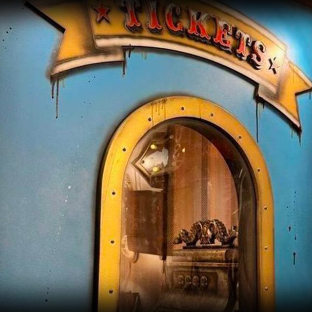 Guichet de fête foraine bleu et jaune sous une banderole Tickets, salle Le cirque hanté chez Freeing à Saint-Maximin