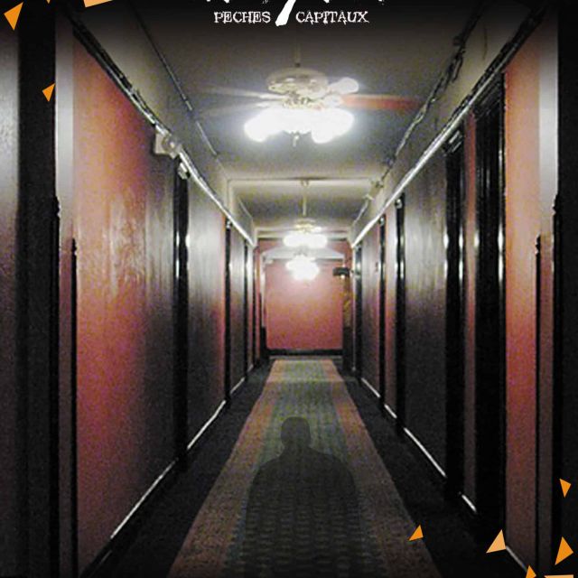 Couloir d'hôtel aux murs rouges et ombre au sol, salle Seven à Crolles