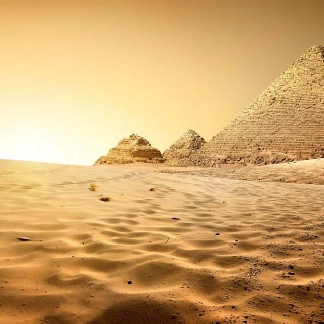 Pyramides et désert égyptien sous un ciel doré, décor de la salle Khéops
