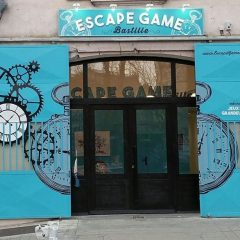 Façade turquoise avec engrenages et cadrans, entrée vitrée de l'Escape game Bastille à Grenoble