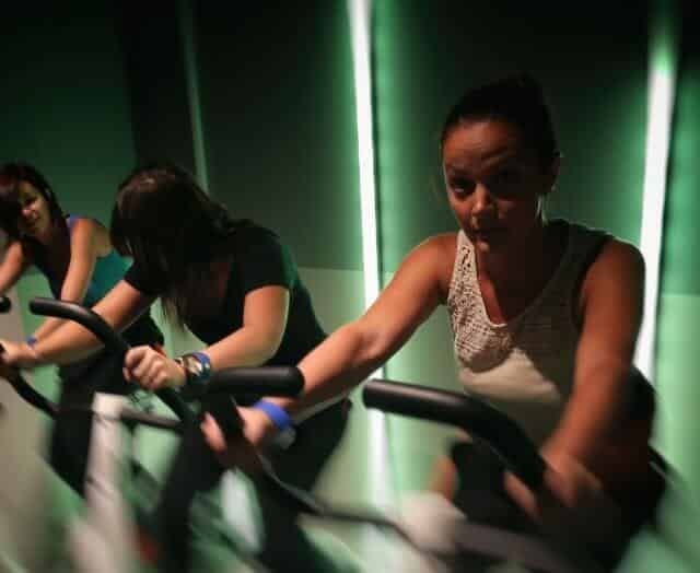 Trois joueurs manipulent des vélos d'exercice dans un couloir aux néons verts chez Winscape Argenteuil