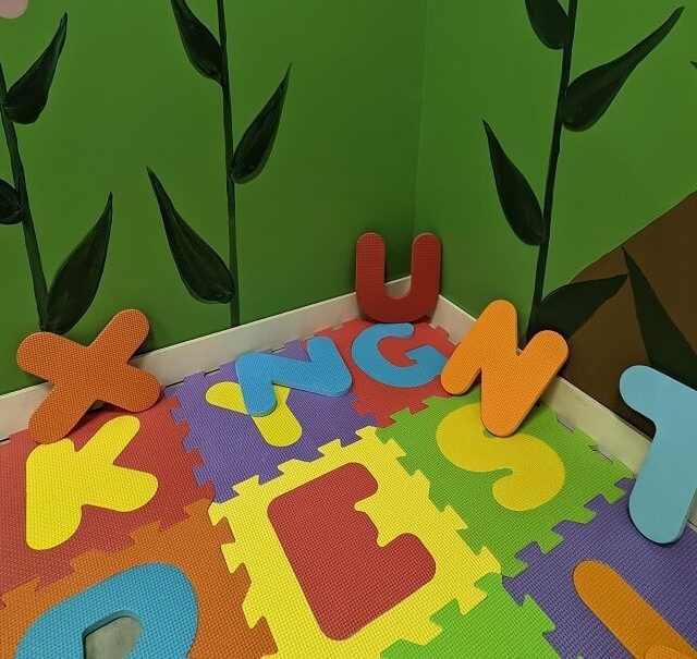 Tapis de mousse à lettres colorées et feuilles vertes peintes au mur, salle Retour en enfance à Sainte-Gemme-la-Plaine