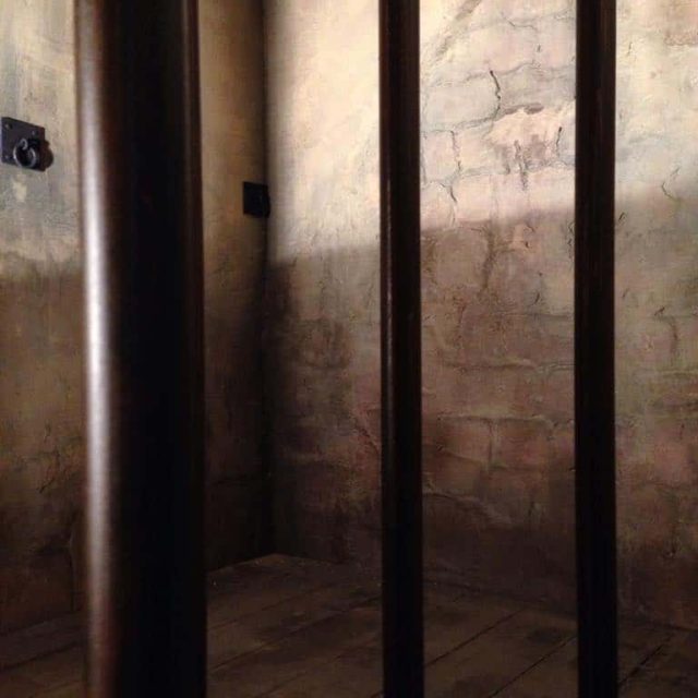 Cellule de prison avec barreaux métalliques et murs en béton brut chez TooLate Bayonne