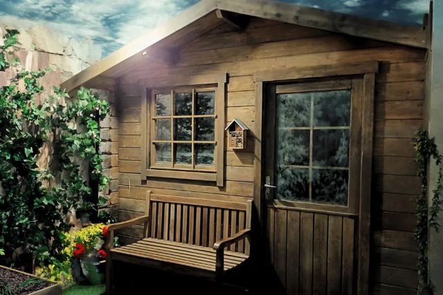 Cabane en bois avec banc, fenêtres et plantes, décor d'aventure chez La Synapserie à Riom