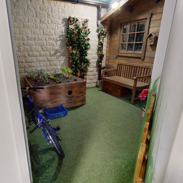 Décor de jardin intérieur avec plantes, banc en bois et vélo bleu chez La Synapserie à Riom