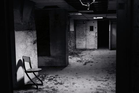 Sous-sol désaffecté aux murs décorés, chaise vide, ambiance d'asile psychiatrique chez Fug game