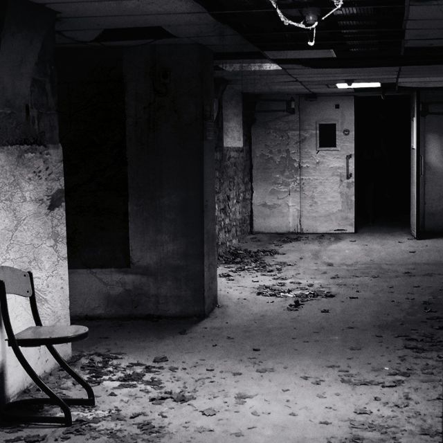 Sous-sol désaffecté aux murs décorés, chaise vide, ambiance d'asile psychiatrique chez Fug game