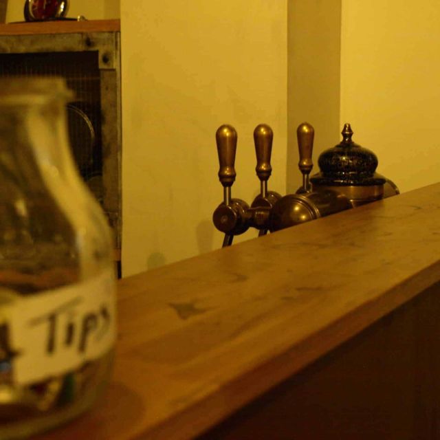 Bar aux lumières jaunes, pot à pourboires et clochette sur le comptoir, salle Le code bar à Paris