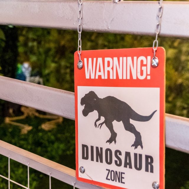 Panneau d'avertissement dinosaure suspendu à une clôture, Jurassic City à Marseille
