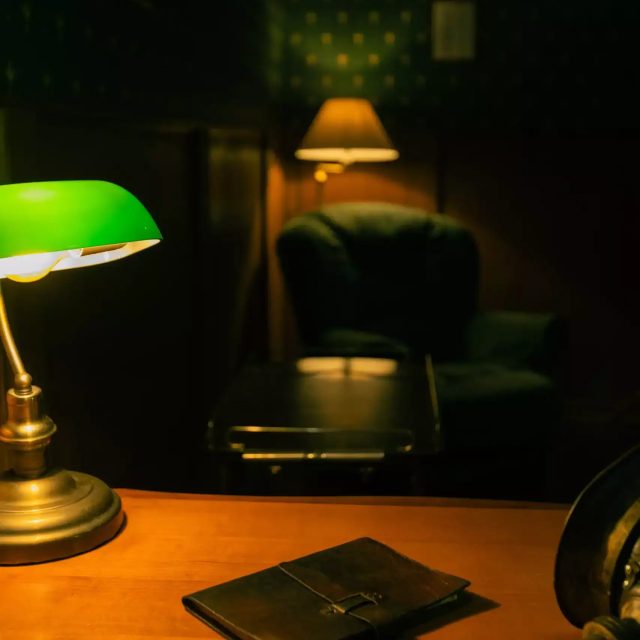 Bureau sombre avec lampe verte, bureau en bois, objets d'enquête chez Crack the egg