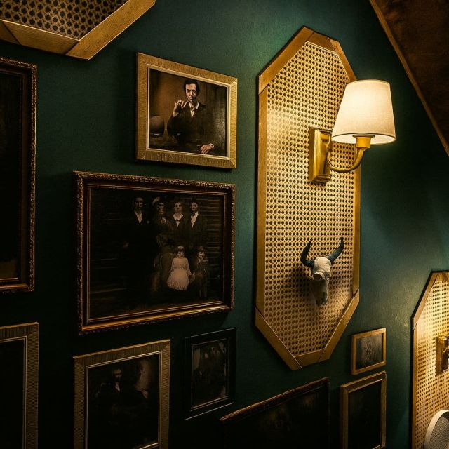 Murs verts, cadres dorés, portraits anciens et appliques murales dans la salle Escape with Sherlock chez Mastermind