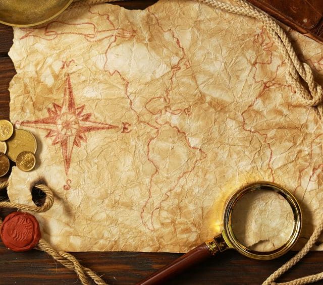 Carte au trésor vieillie avec pièces d'or, loupe et sceau rouge sur bois