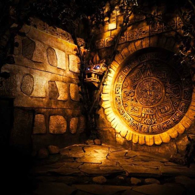 Porte ronde dorée gravée de motifs dans un mur de pierre éclairé, salle Tomb Hunter chez Freeing à Saint-Maximin