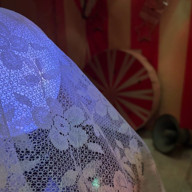 Grande cloche de dentelle blanche éclairée de bleu devant une roue de cirque, salle Circus à Laxou